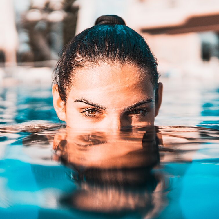 injectables patient model with black hair and brown eyes swimming in a pool